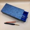 a blue box with a lid open and two crochet hooks