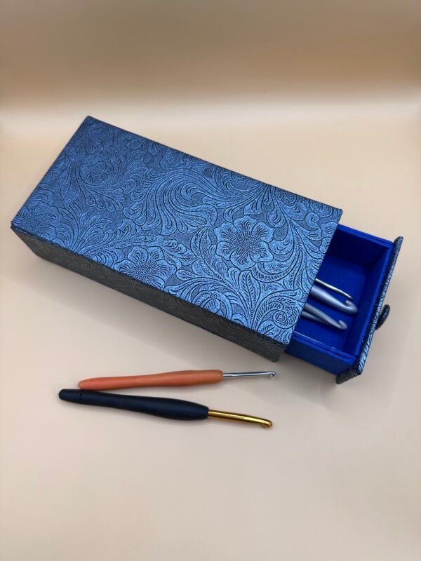 a blue box with a lid open and two crochet hooks
